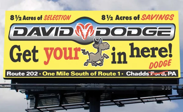 Yellow David Dodge billboard: 8½ acres of selection, 8½ acres of savings, with a cartoon donkey